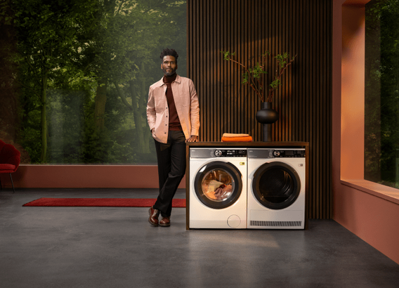 Homme debout à côté d'une machine à laver AEG.