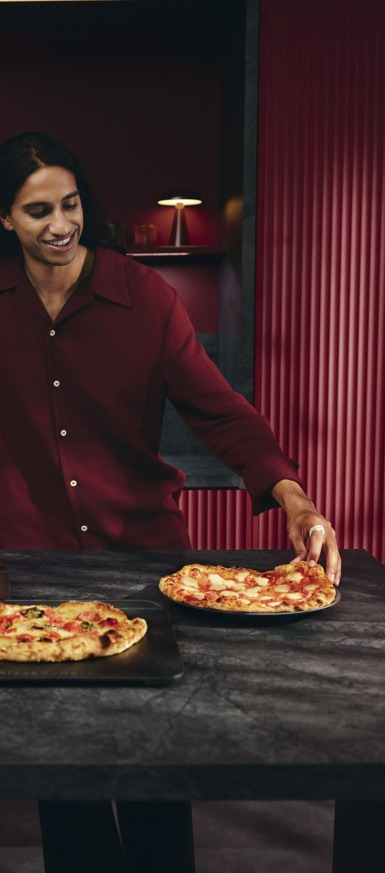 Femme debout à côté d’une pizza